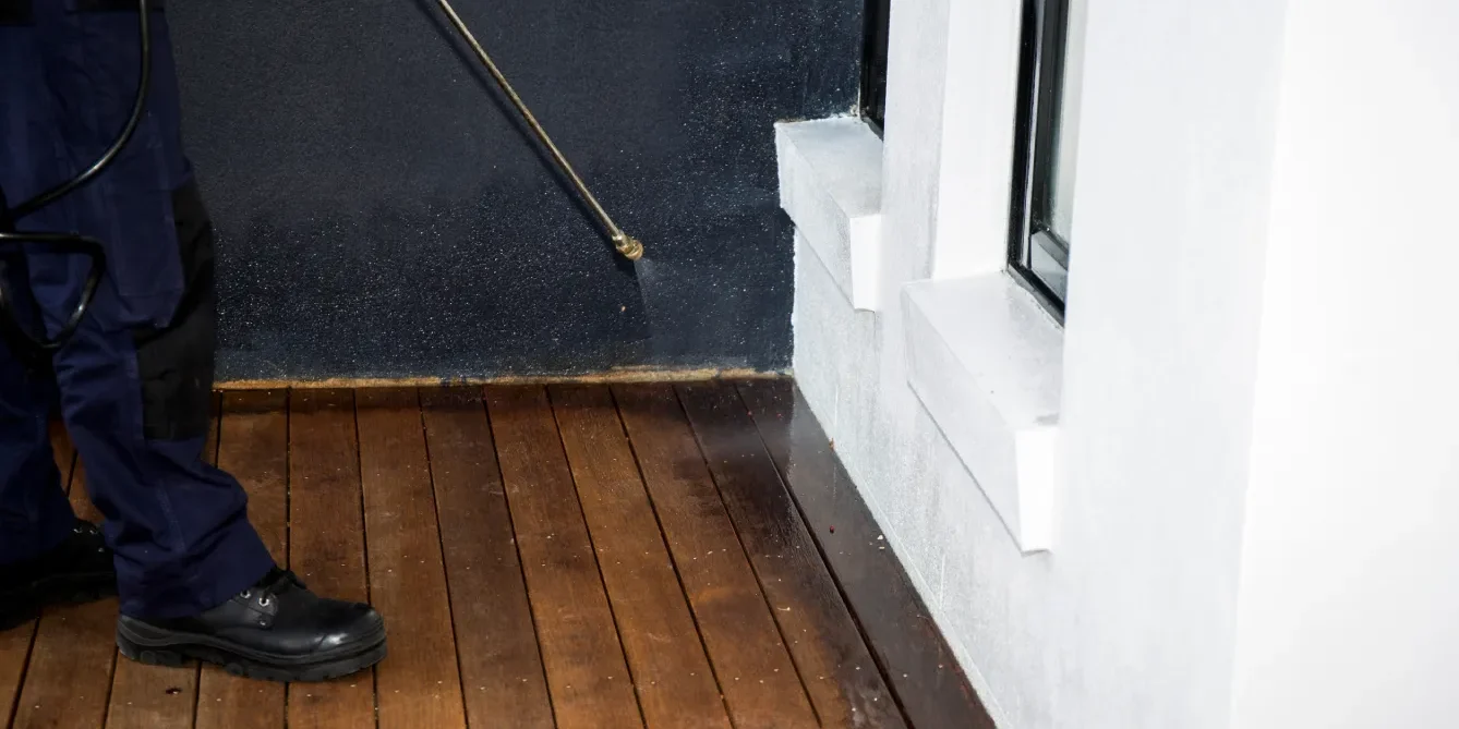 A pest control technician applying year-round residential spray Phoenix homes need along the exterior perimeter and entry points.