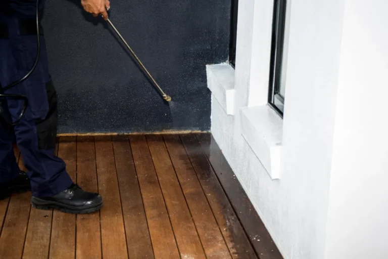 A pest control technician applying year-round residential spray Phoenix homes need along the exterior perimeter and entry points.
